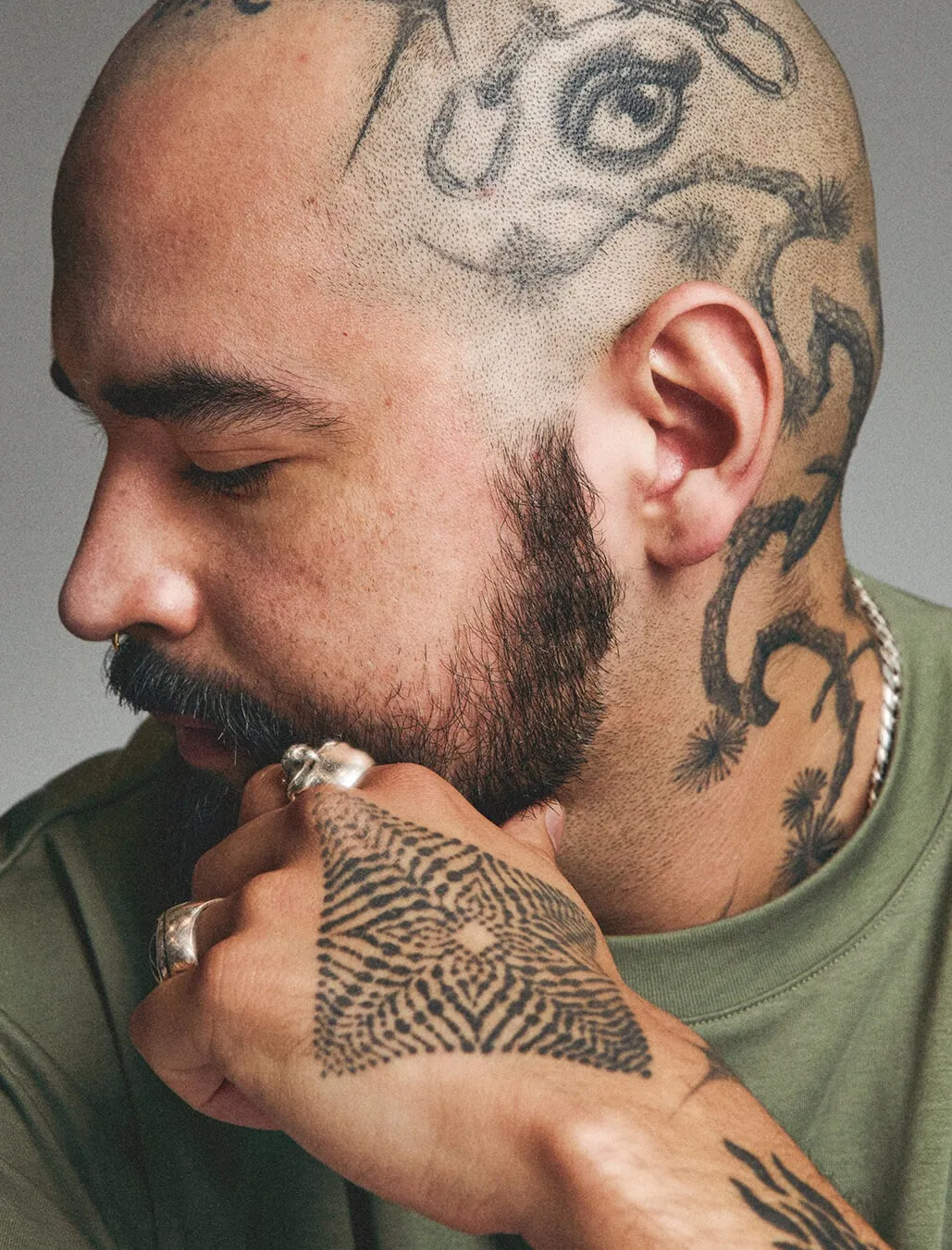 Closeup portrait of a tattoo artist showing off his hand and scalp tattoos